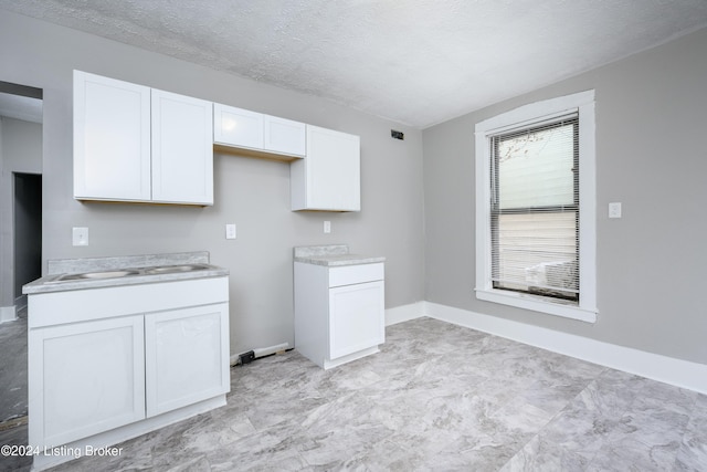 kitchen featuring white cabinets, a textured ceiling, and sink