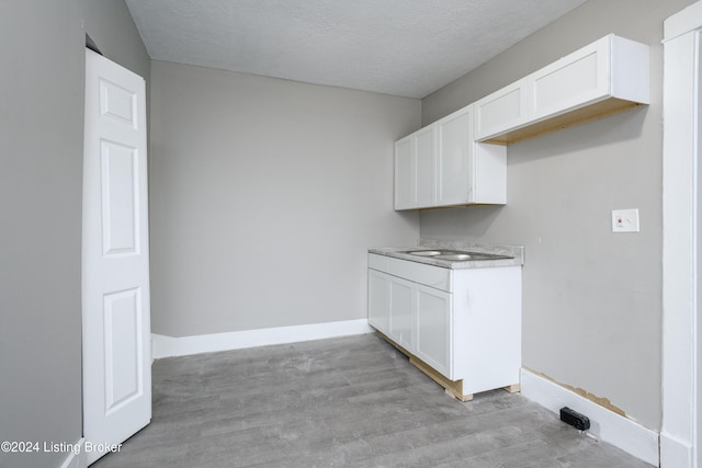 laundry room featuring light wood-type flooring, a textured ceiling, and sink