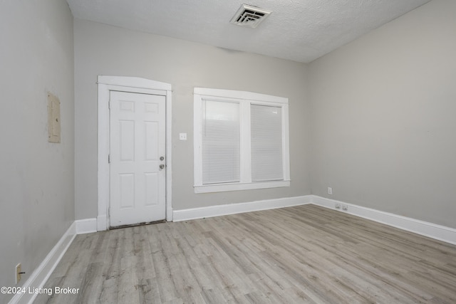 empty room featuring light wood-type flooring and a textured ceiling