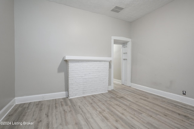 spare room featuring light hardwood / wood-style flooring and a textured ceiling