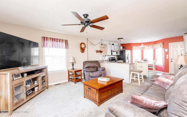 living room featuring light carpet, a healthy amount of sunlight, and ceiling fan