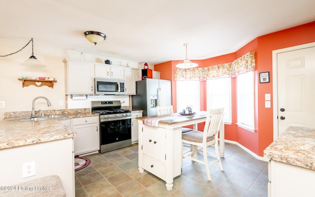 kitchen featuring sink, hanging light fixtures, stainless steel appliances, white cabinets, and a breakfast bar