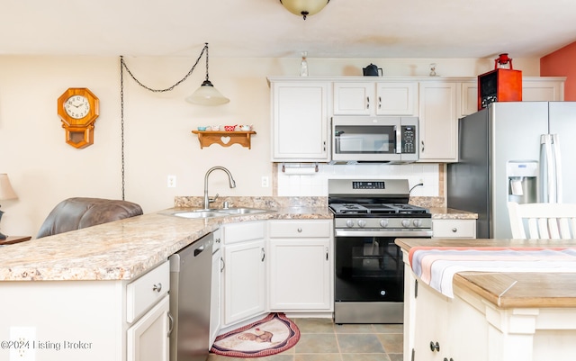 kitchen featuring sink, kitchen peninsula, hanging light fixtures, white cabinetry, and stainless steel appliances