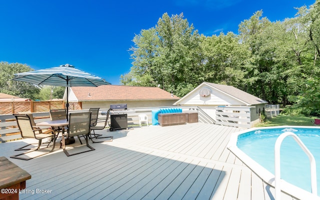 view of pool with area for grilling, a deck, and an outbuilding