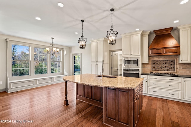 kitchen with stainless steel appliances, custom range hood, decorative light fixtures, and hardwood / wood-style flooring