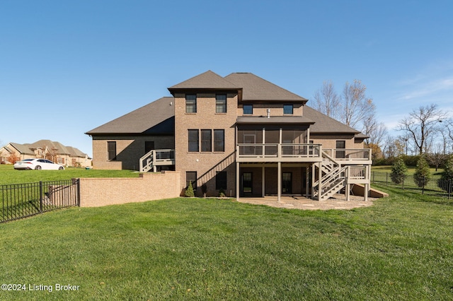 back of property featuring a wooden deck, a lawn, a patio, and a sunroom