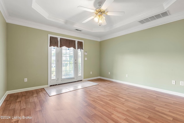 spare room with light hardwood / wood-style floors, ceiling fan, a tray ceiling, and ornamental molding