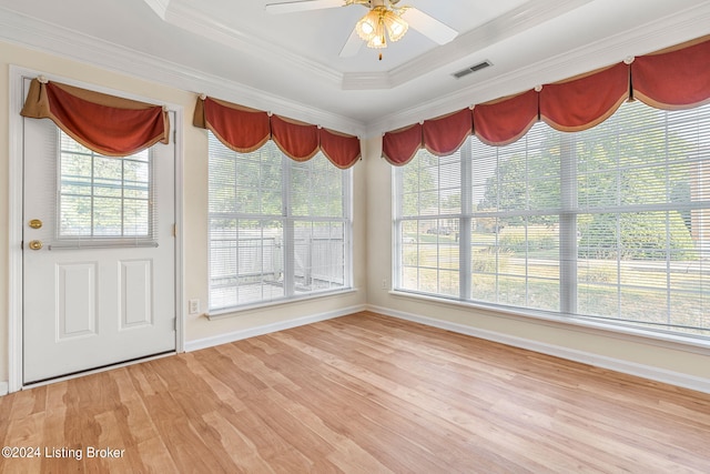 unfurnished sunroom featuring a wealth of natural light, ceiling fan, and a tray ceiling