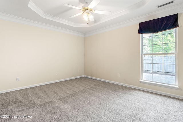 carpeted empty room with ceiling fan, a raised ceiling, and ornamental molding