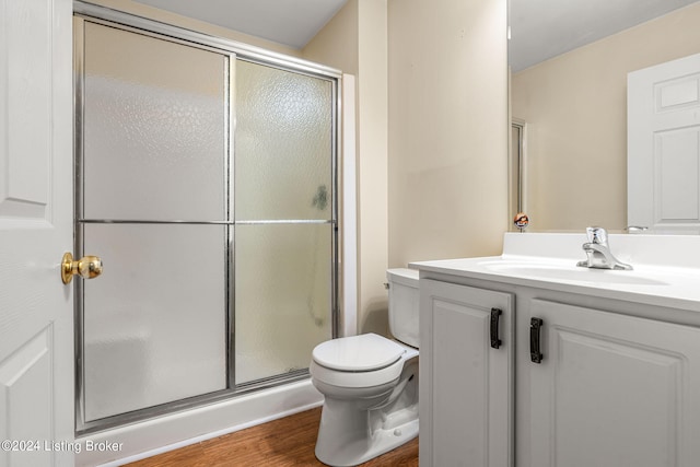 bathroom featuring wood-type flooring, vanity, a shower with door, and toilet