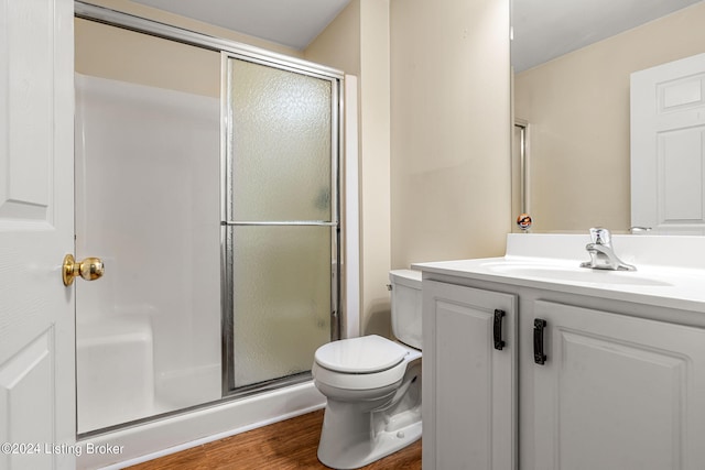 bathroom with hardwood / wood-style flooring, a shower with shower door, vanity, and toilet