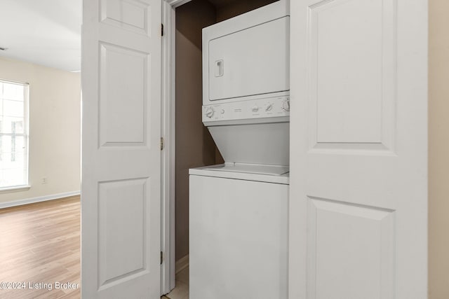 washroom with light hardwood / wood-style flooring and stacked washer / drying machine