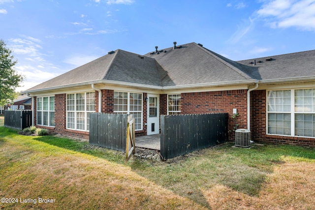 rear view of house featuring central air condition unit, a lawn, and a patio