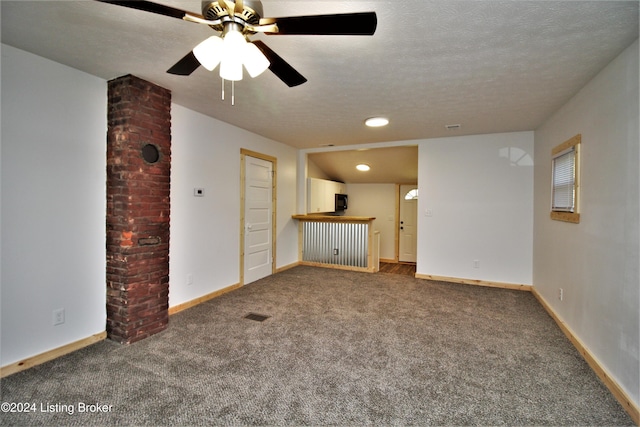 unfurnished living room with a dry bar, baseboards, a ceiling fan, a textured ceiling, and carpet floors