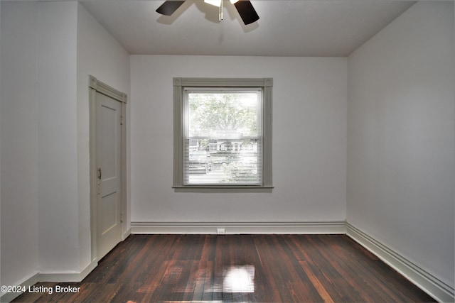 empty room featuring a ceiling fan, dark wood-style flooring, and baseboards