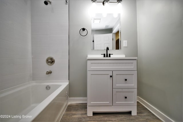 bathroom featuring vanity, baseboards, wood finished floors, and shower / bathtub combination