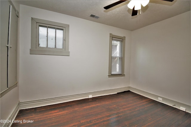 unfurnished room featuring visible vents, a ceiling fan, dark wood-style flooring, baseboard heating, and a textured ceiling