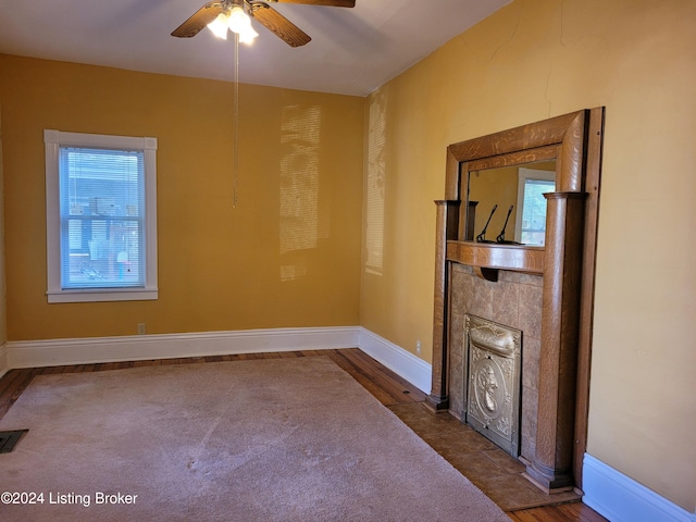 spare room with a fireplace, dark hardwood / wood-style floors, and ceiling fan