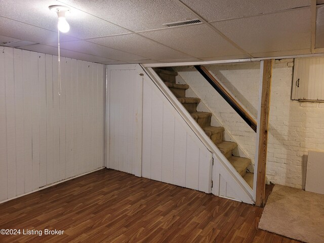 basement featuring dark hardwood / wood-style floors and a paneled ceiling