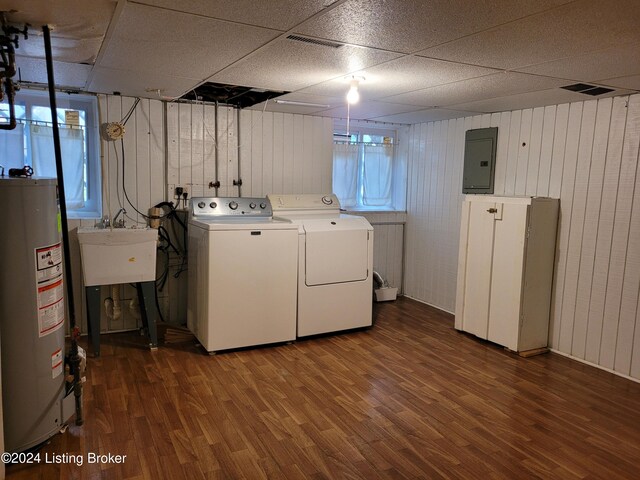 washroom with wood walls, washing machine and dryer, wood-type flooring, water heater, and electric panel