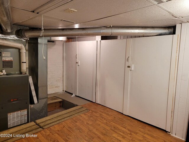 basement with light hardwood / wood-style flooring and heating unit