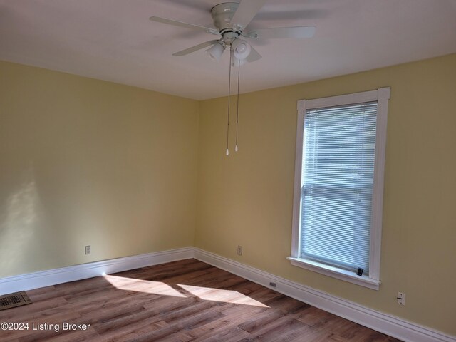 unfurnished room featuring a wealth of natural light, hardwood / wood-style floors, and ceiling fan