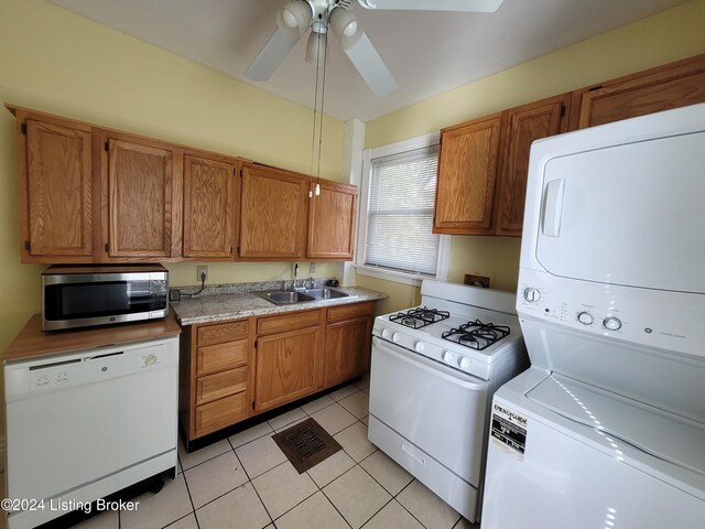 kitchen featuring white appliances, sink, ceiling fan, light tile patterned floors, and stacked washer and clothes dryer