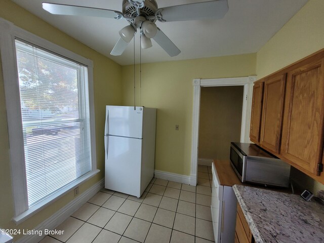 kitchen with light tile patterned flooring, white fridge, and ceiling fan