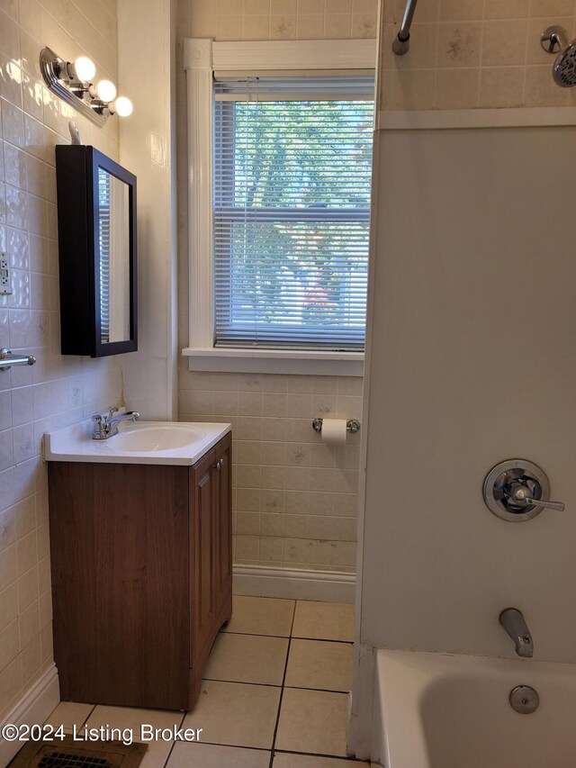 bathroom featuring vanity, bathtub / shower combination, tile walls, and tile patterned flooring