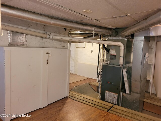 basement with wood-type flooring and heating unit