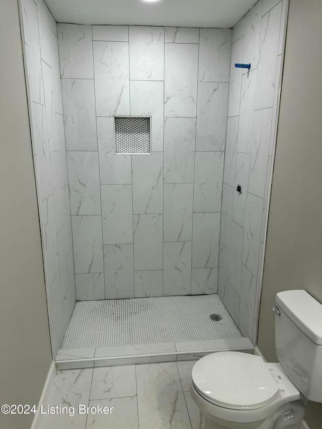 bathroom featuring a tile shower and toilet