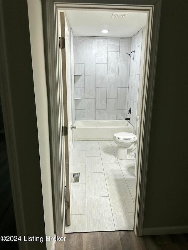 bathroom with toilet, tiled shower / bath combo, and wood-type flooring