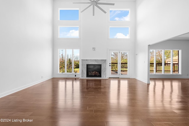 unfurnished living room featuring a towering ceiling, a wealth of natural light, and dark wood-type flooring