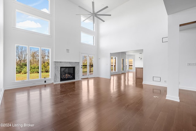 unfurnished living room featuring hardwood / wood-style floors, ceiling fan, and a high ceiling