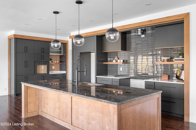 kitchen with dark stone counters, tasteful backsplash, decorative light fixtures, and dark hardwood / wood-style floors