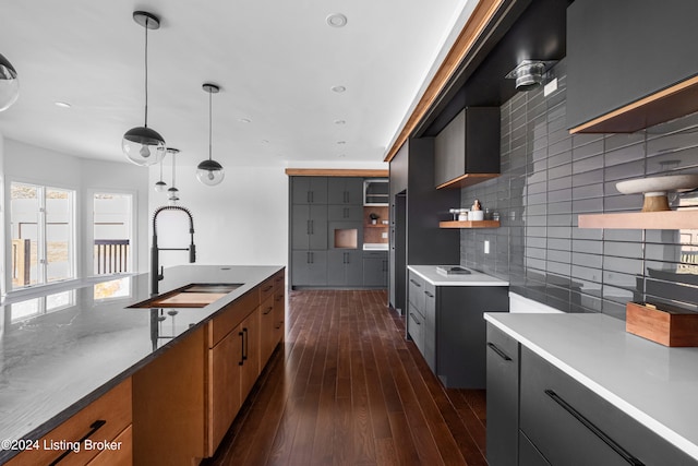 kitchen featuring decorative backsplash, hanging light fixtures, sink, and dark hardwood / wood-style floors