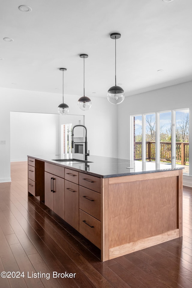 bar with dark hardwood / wood-style flooring, pendant lighting, light brown cabinets, and sink