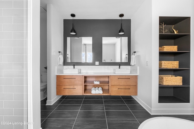 bathroom with tile patterned flooring, a tub, vanity, and toilet