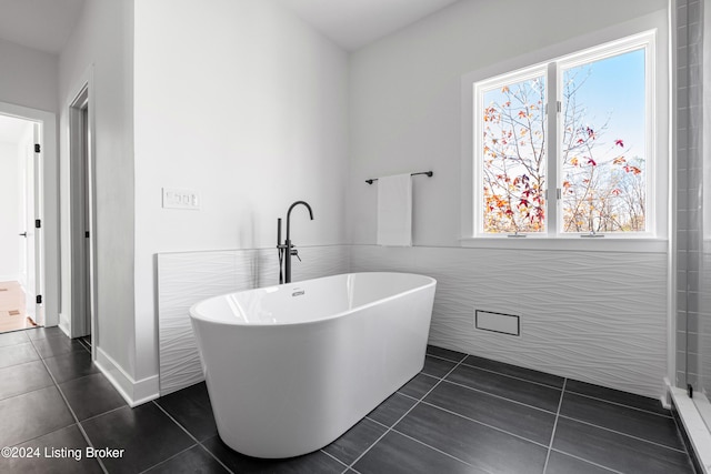 bathroom with a washtub, tile walls, and tile patterned floors