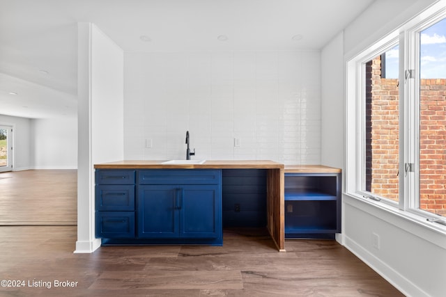 bar with wooden counters, dark wood-type flooring, sink, tasteful backsplash, and blue cabinetry