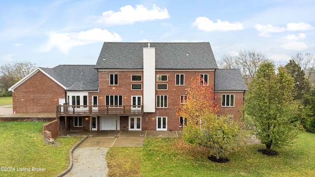 rear view of house with a deck, a lawn, french doors, and a patio area