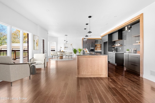 kitchen with hanging light fixtures, dark hardwood / wood-style floors, backsplash, and a center island