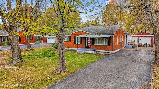 bungalow-style home with a front yard, an outbuilding, brick siding, and a detached garage