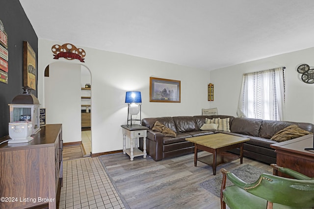 living area with baseboards, arched walkways, and wood finished floors