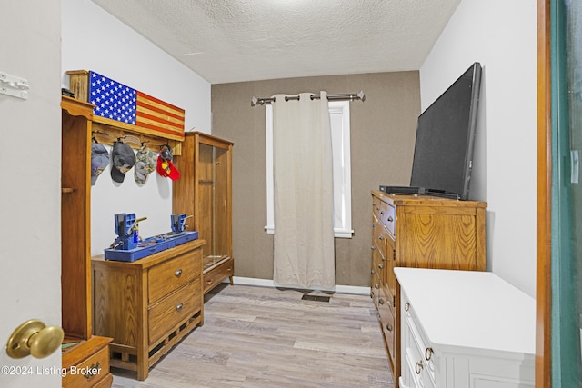 bedroom with baseboards, light wood-style floors, and a textured ceiling