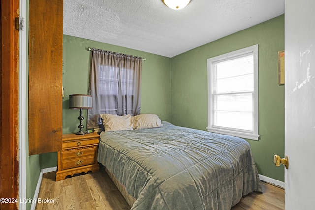 bedroom featuring wood finished floors, baseboards, and a textured ceiling