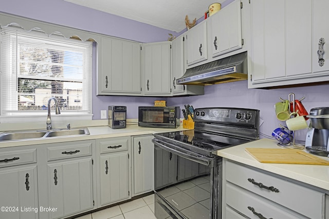 kitchen featuring light countertops, black range with electric cooktop, under cabinet range hood, and a sink