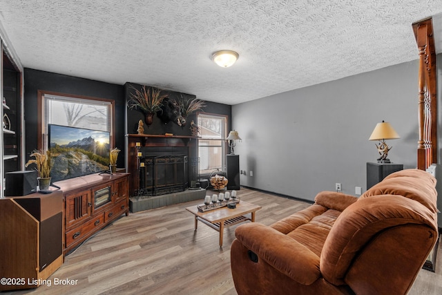 living room with a fireplace, wood finished floors, baseboards, and a textured ceiling