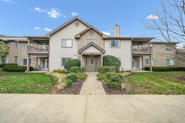 view of property with a front yard and a balcony