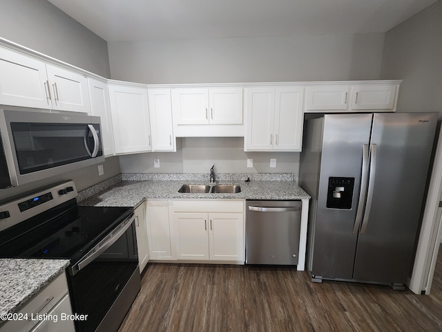 kitchen with stainless steel appliances, sink, light stone counters, white cabinets, and dark hardwood / wood-style flooring